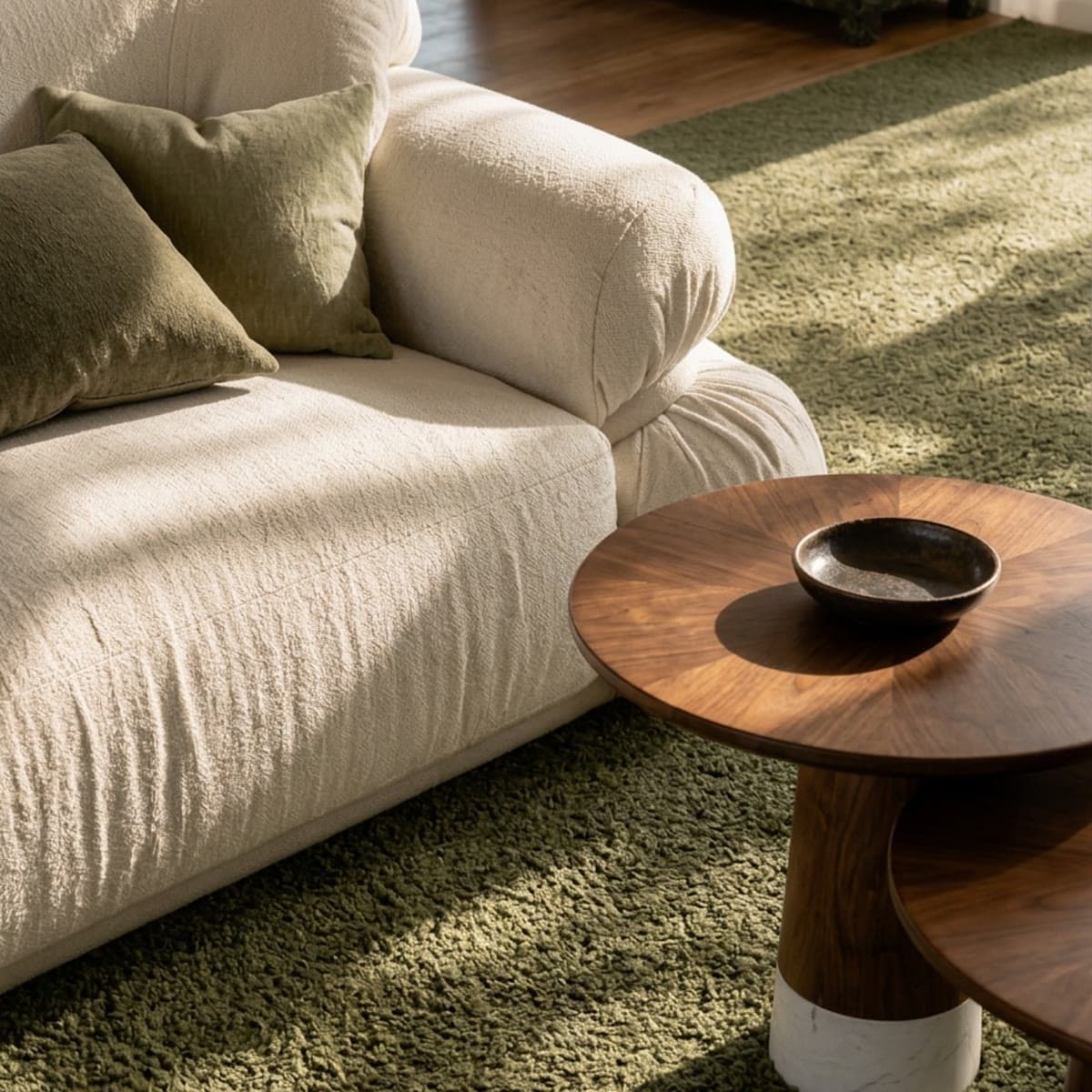 Close-up render of a boucle sofa with green cushions and a timber side table on the sage green carpet at Lanes Road